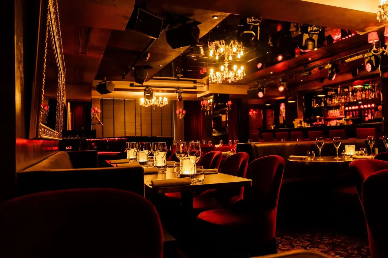 Dark, elegant speakeasy-style lounge with velvet seating and warm chandeliers