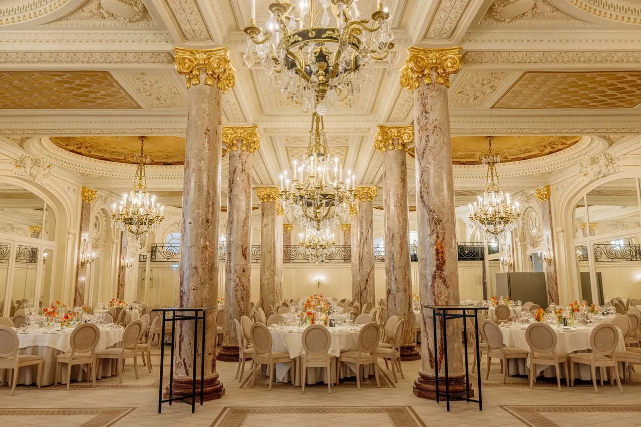 Gilded ballroom with marble columns and crystal chandeliers set for a gala dinner