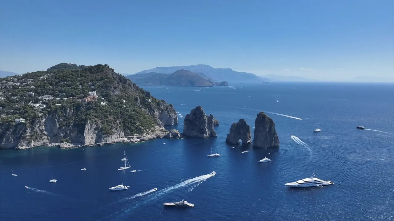 Aerial view of dramatic sea stacks off a Mediterranean island with yachts below