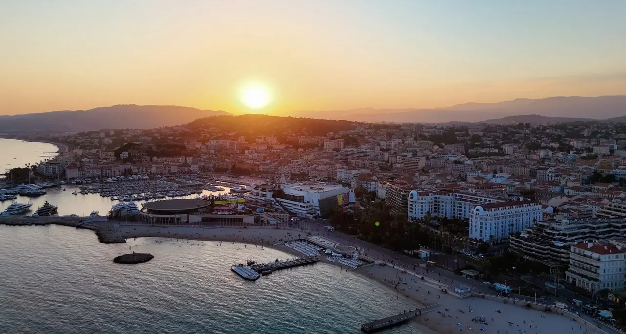 Aerial view of a French Riviera bay and marina at sunset, the old town glowing gold