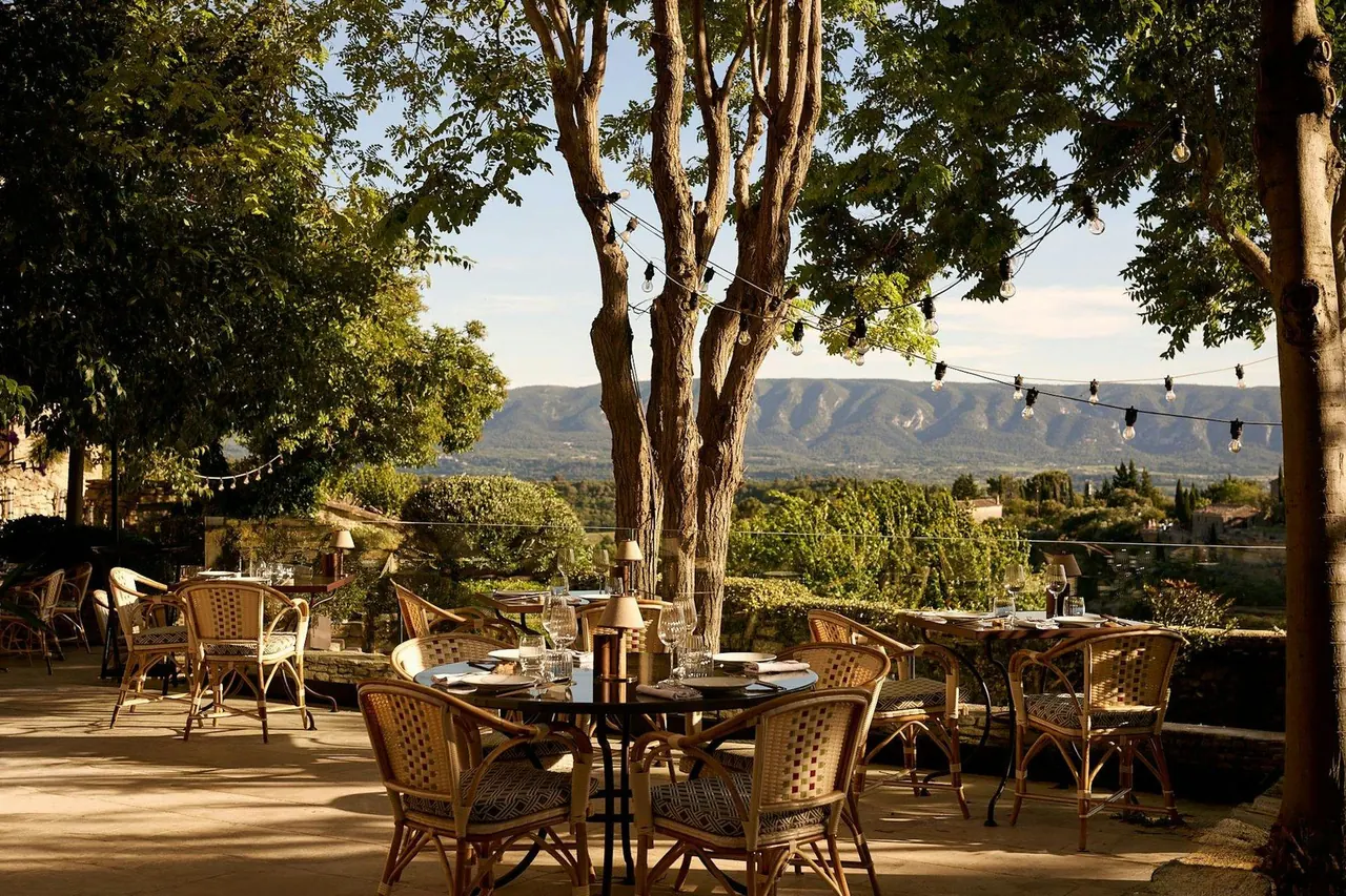 Shaded restaurant terrace with string lights overlooking a countryside valley