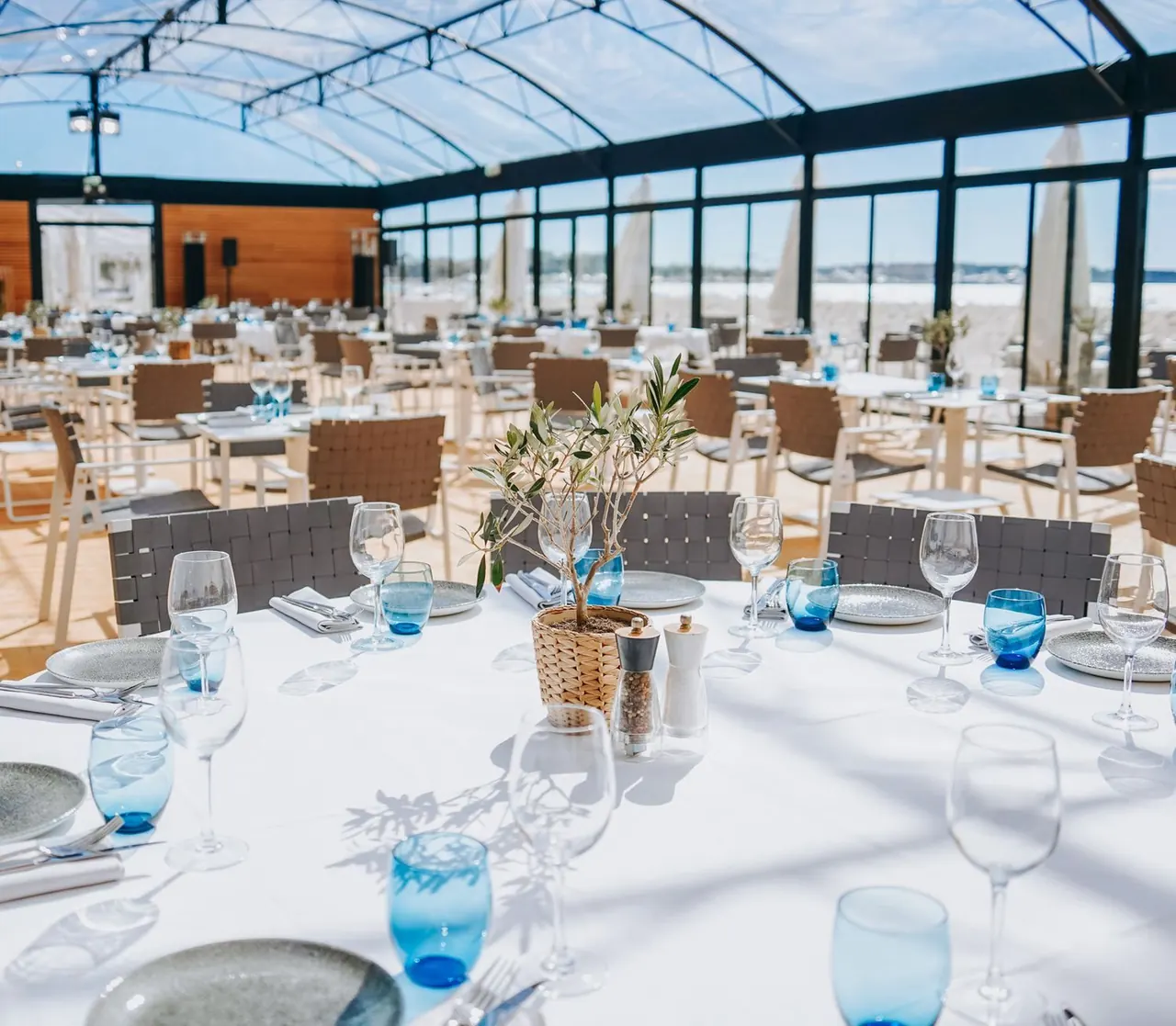 Glass-roofed seaside dining room set for lunch with a beach view