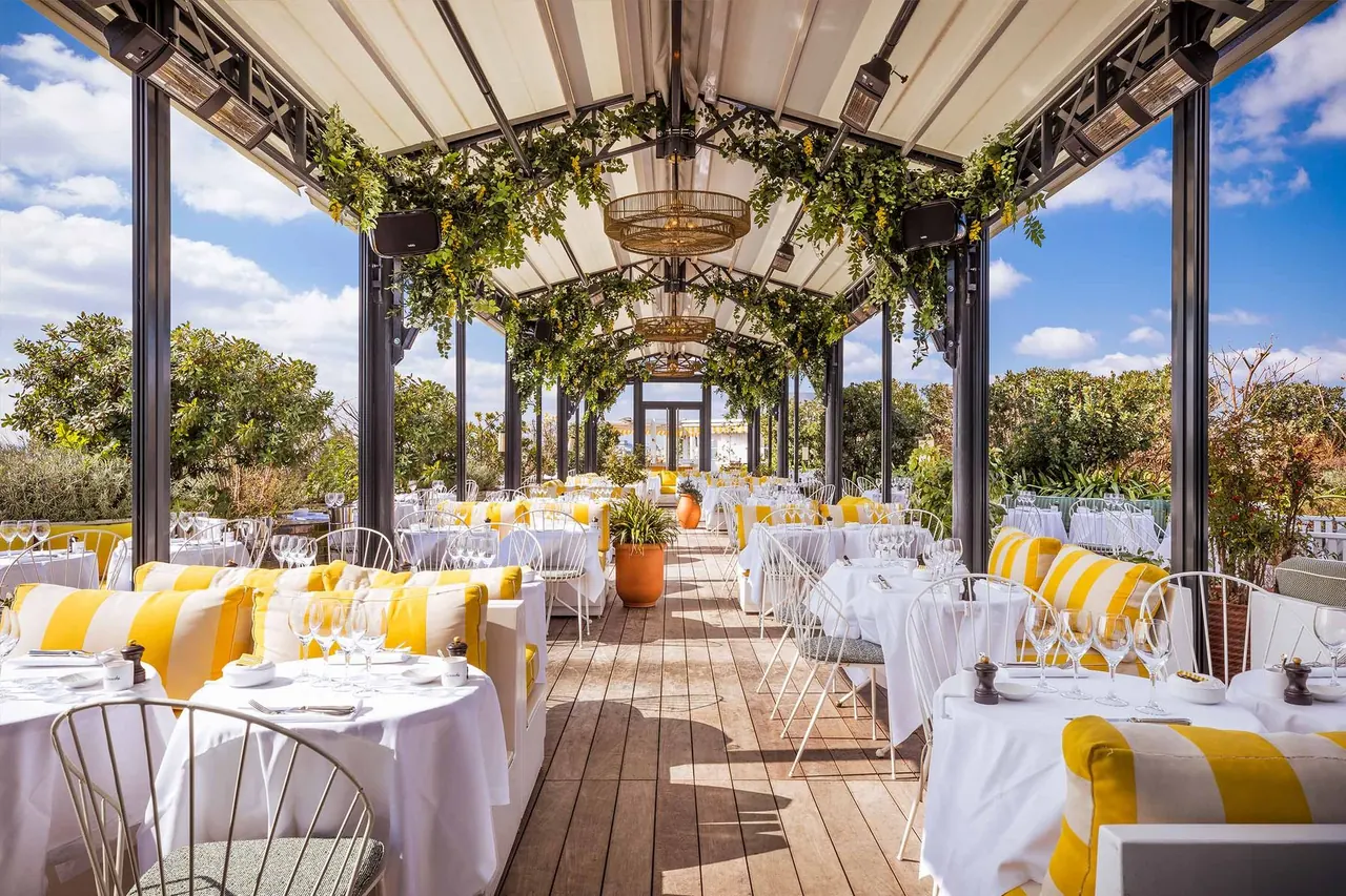 Covered terrace restaurant with striped upholstery and lush greenery