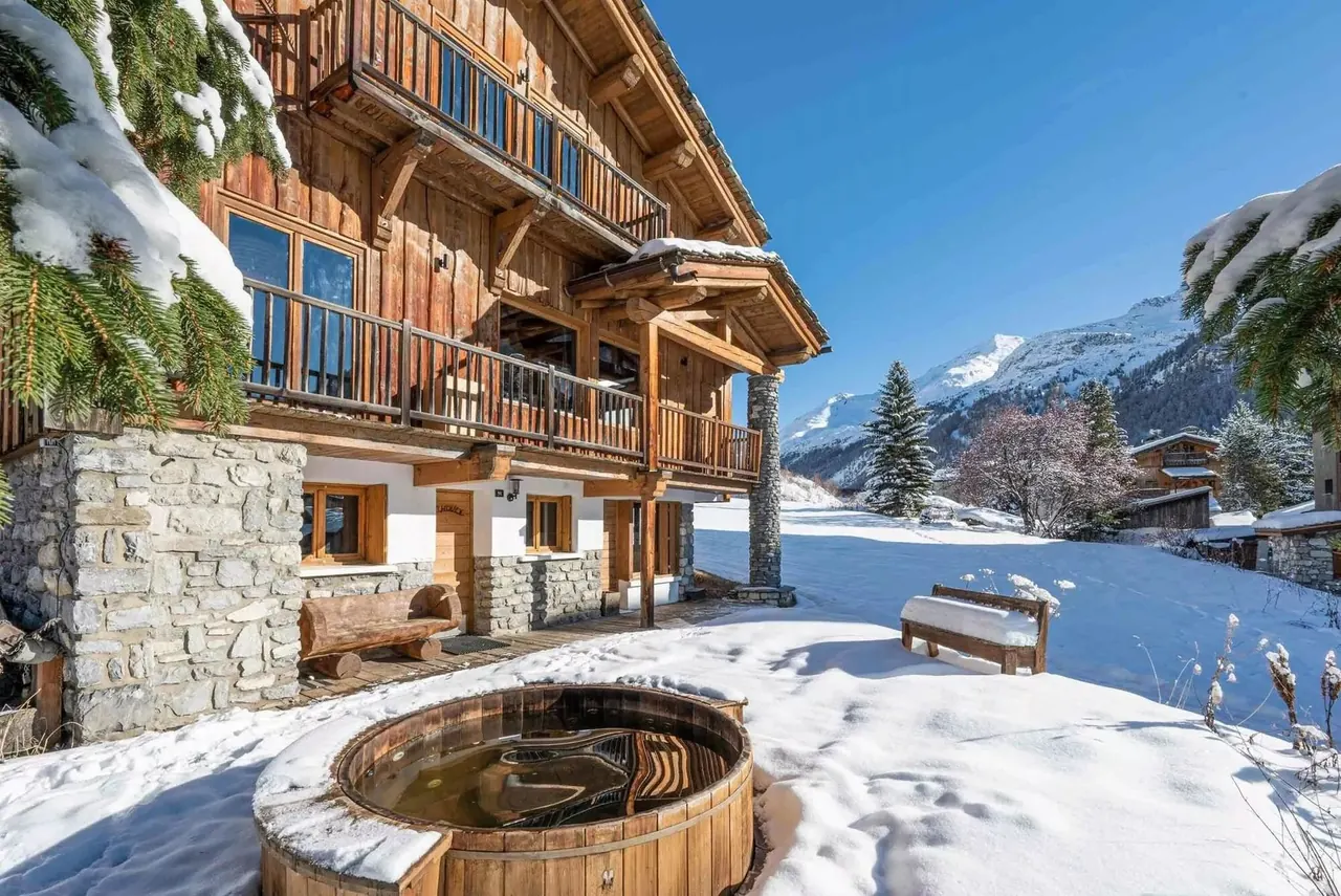 Snow-covered ski chalet exterior with a private outdoor hot tub and mountain views