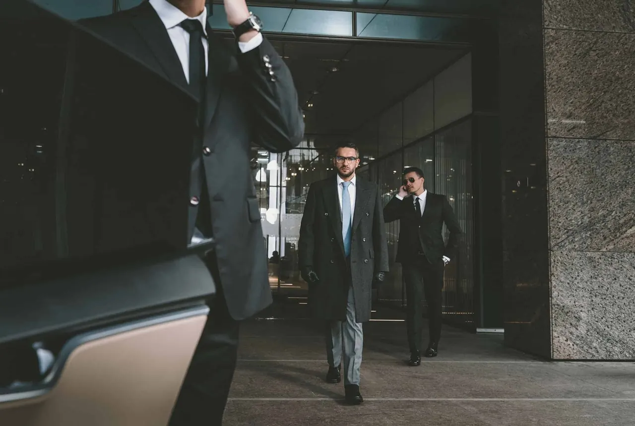 Two security professionals escorting a principal through a modern lobby