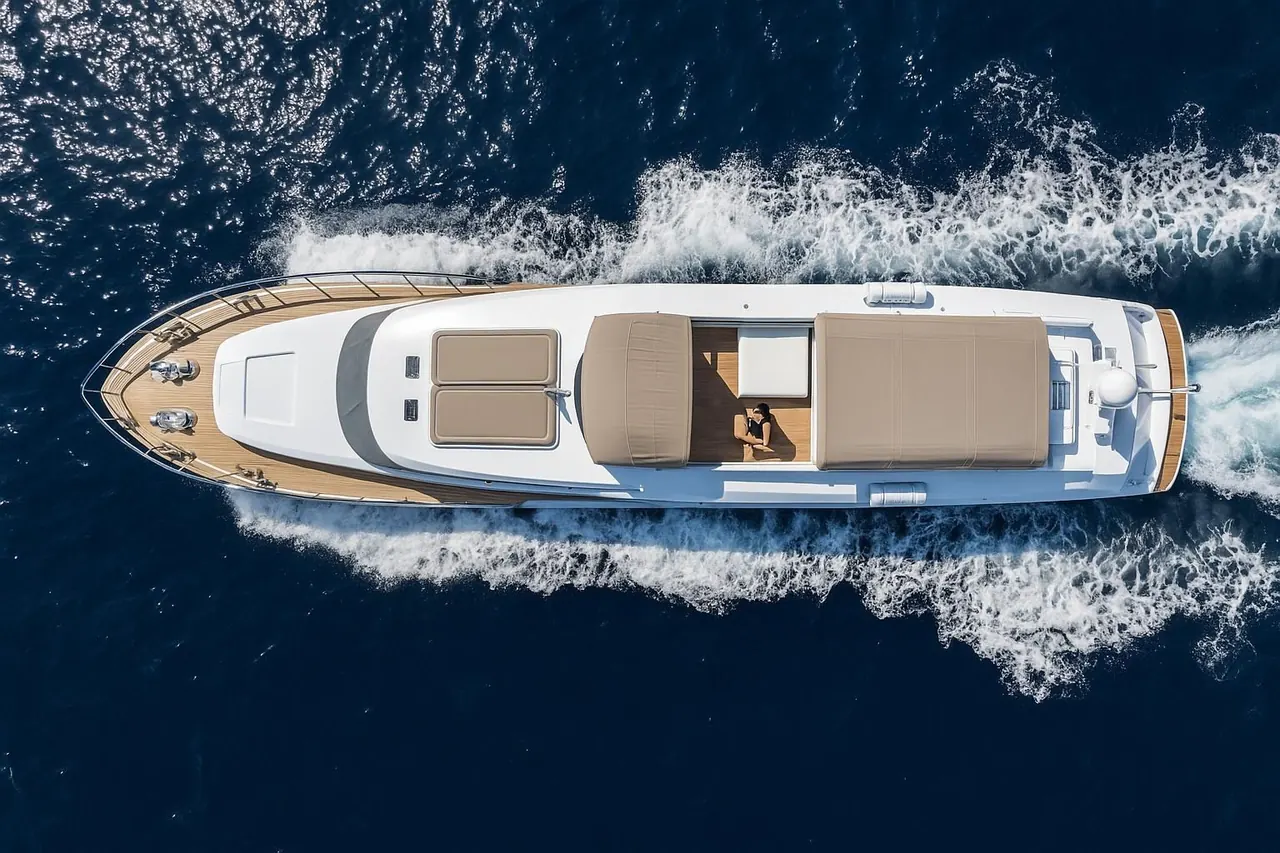 Aerial view of a motor yacht cruising with a guest relaxing on the foredeck