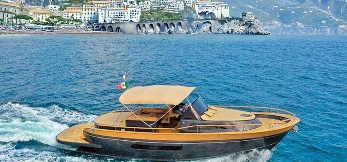 Motor yacht cruising past a colorful Amalfi Coast town